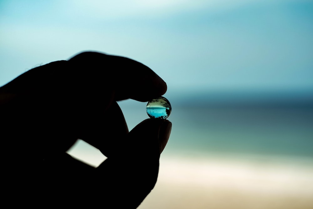 a person holding a small glass object in their hand