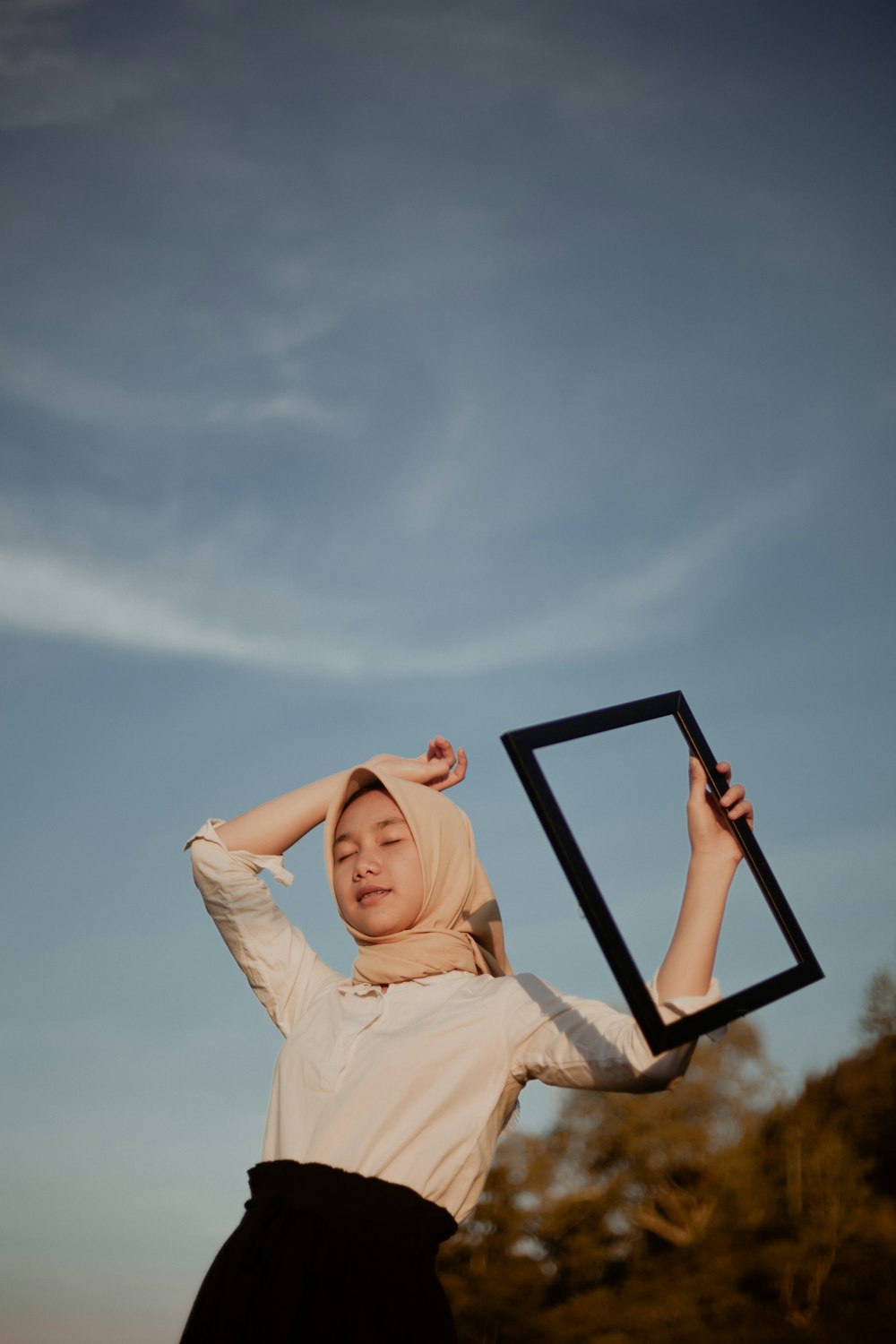 close-up photography of girl standing near outdoor while holding photo frame