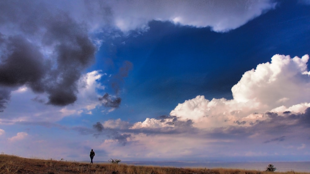 a man standing on top of a dry grass covered field