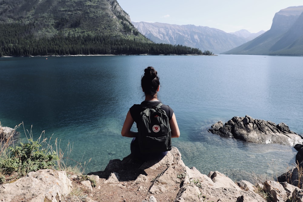 woman with black background facing body of water