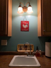 Plumber fixing a residential sink with tools in a well-lit kitchen.