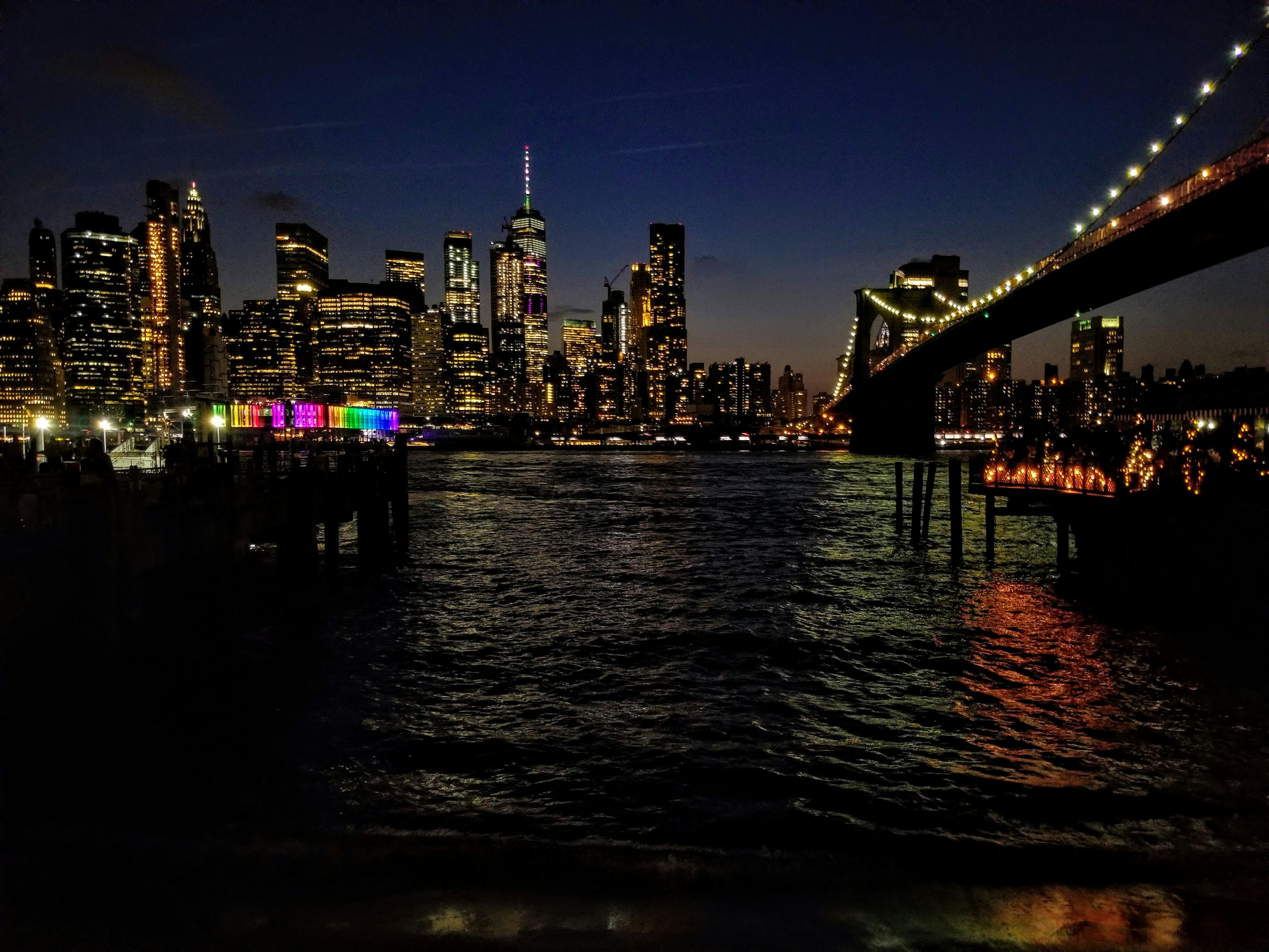 body of water near bridge and buildings at nighttime