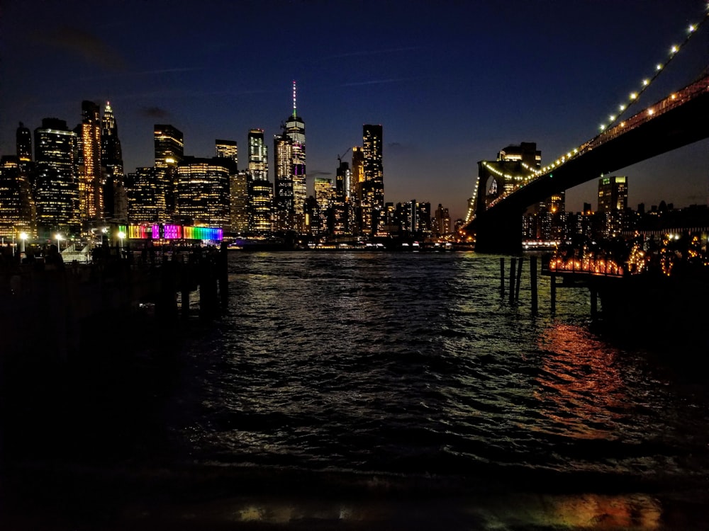 body of water near bridge and buildings at nighttime