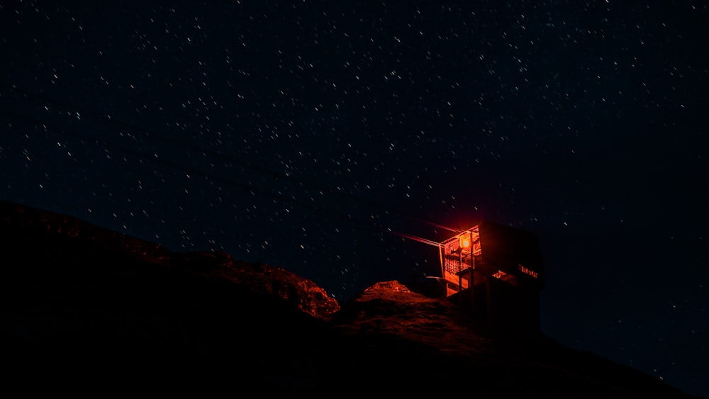 uma pequena torre sentada no topo de uma colina sob um céu noturno