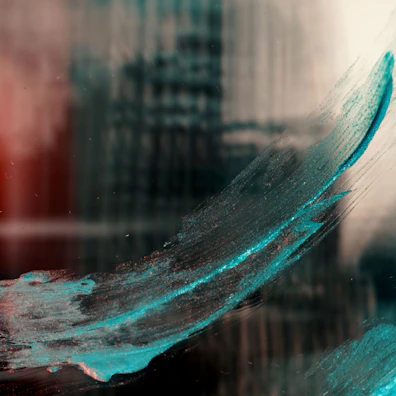 Close-up of a brush stroke adding vibrant teal color to a feature wall.