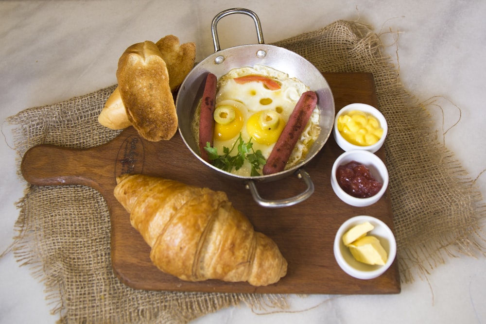 bread beside bowl with eggs and hotdog