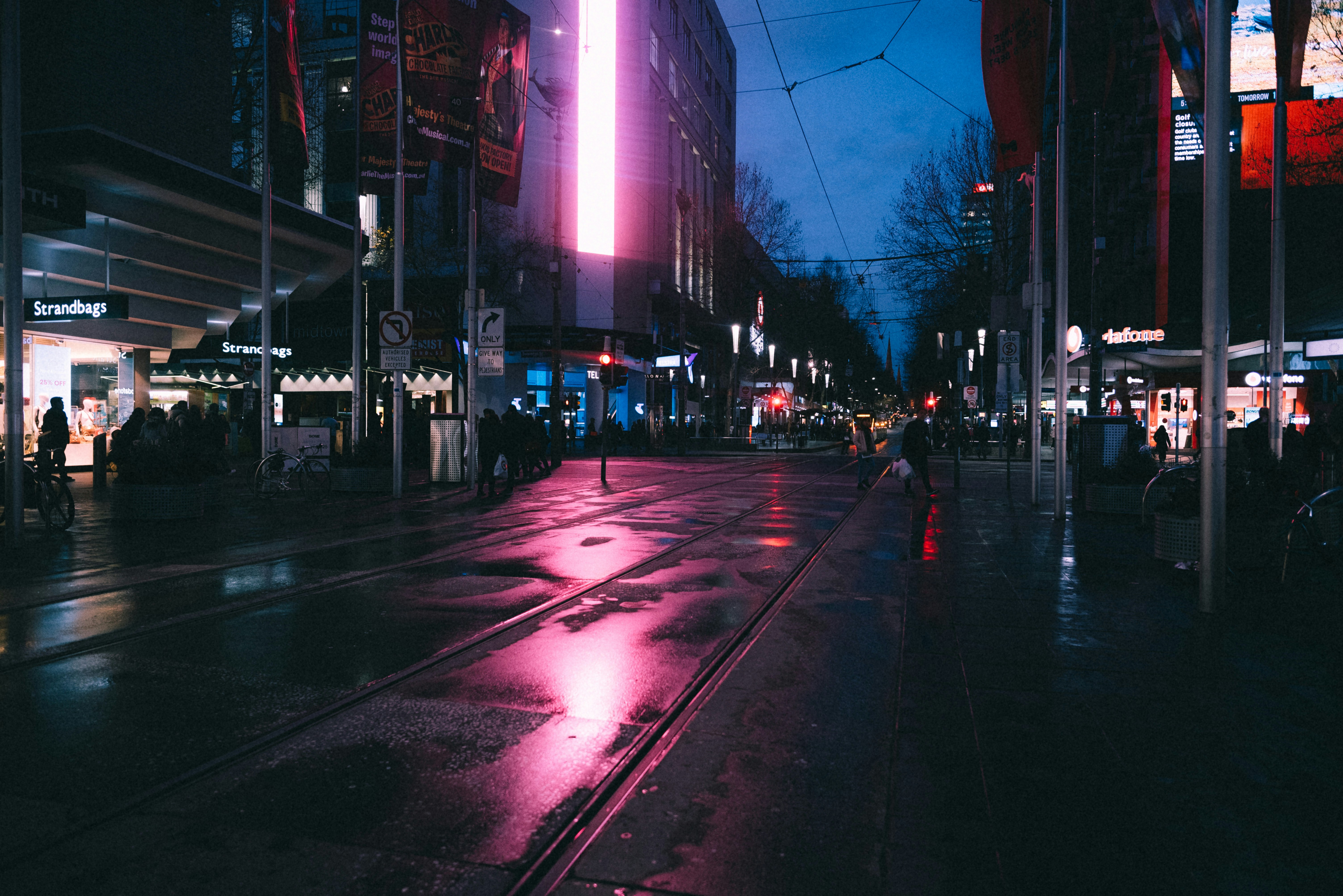 Neon-lit street at dusk with reflective puddles