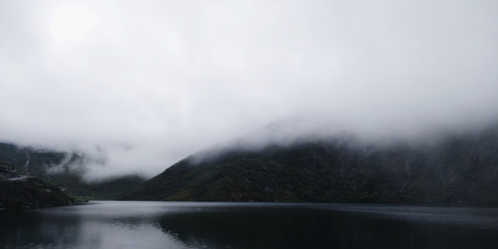 a body of water surrounded by mountains and fog