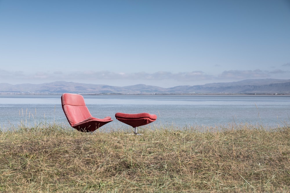 red glider chair beside body of water at daytime