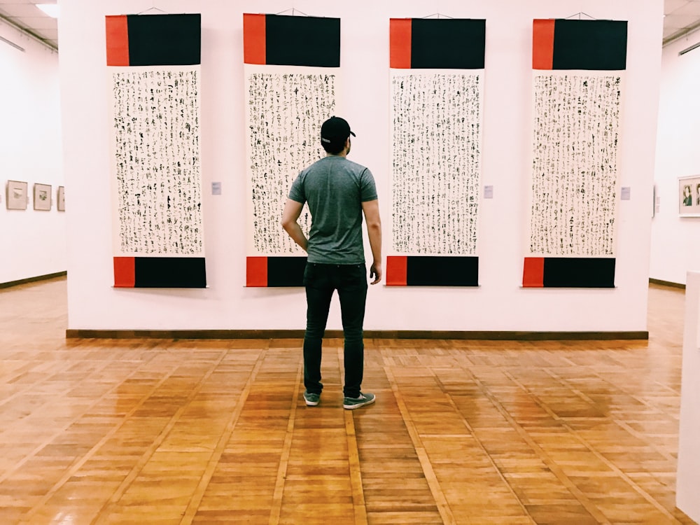 man standing on floor tiles and looking at wall