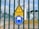 A fenced area with warning signs is visible. The yellow triangular sign includes a lightning bolt symbol and the German text 'Hochspannung Lebensgefahr,' indicating high voltage and danger to life. Below it is a blue circular sign with an icon of a person wearing a hard hat, suggesting mandatory safety equipment. Behind the fence, there are electrical installations, possibly part of a transformer station.