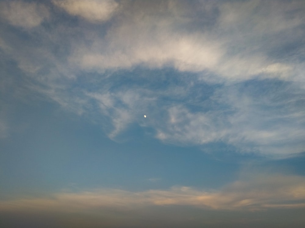 the sky is filled with clouds and a half moon