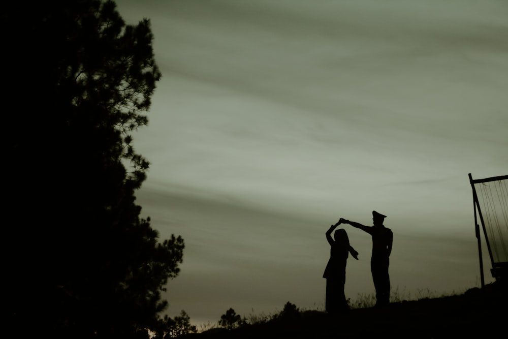 silhouette of dancing couple near tree during night
