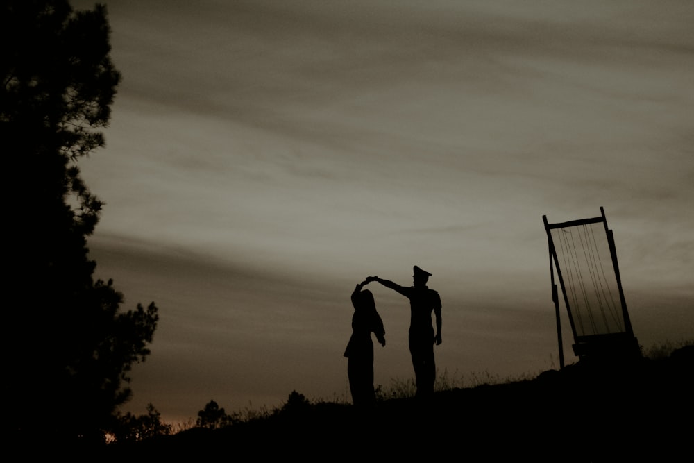 silhouette photography of two persons standing near tree