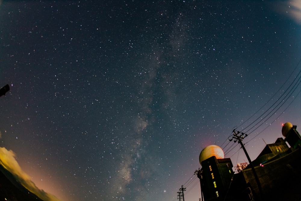 low-angle photo of stars in the sky with silhouette of telephone post