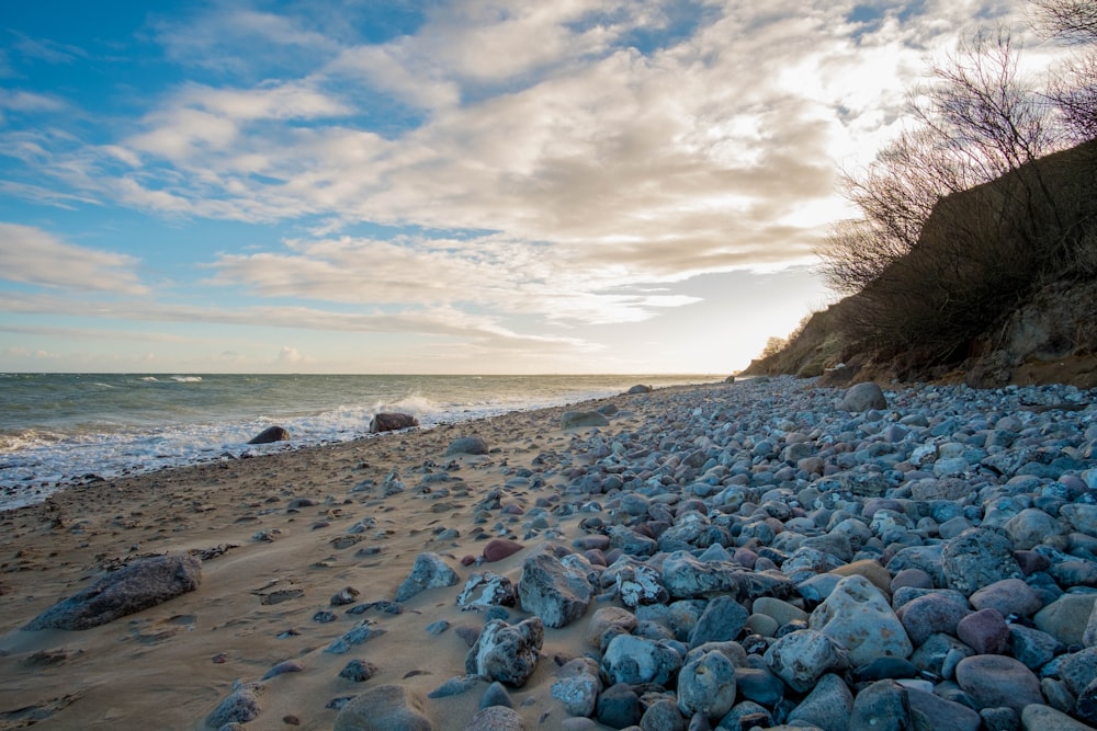 gray rocks beside body of water at daytime