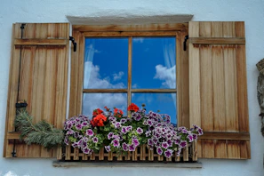A rustic wooden window opening to a garden full of blooming flowers.