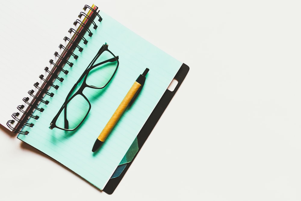 black eyeglasses and brown click pen