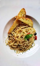 A beautifully arranged plate of pasta with garlic bread.