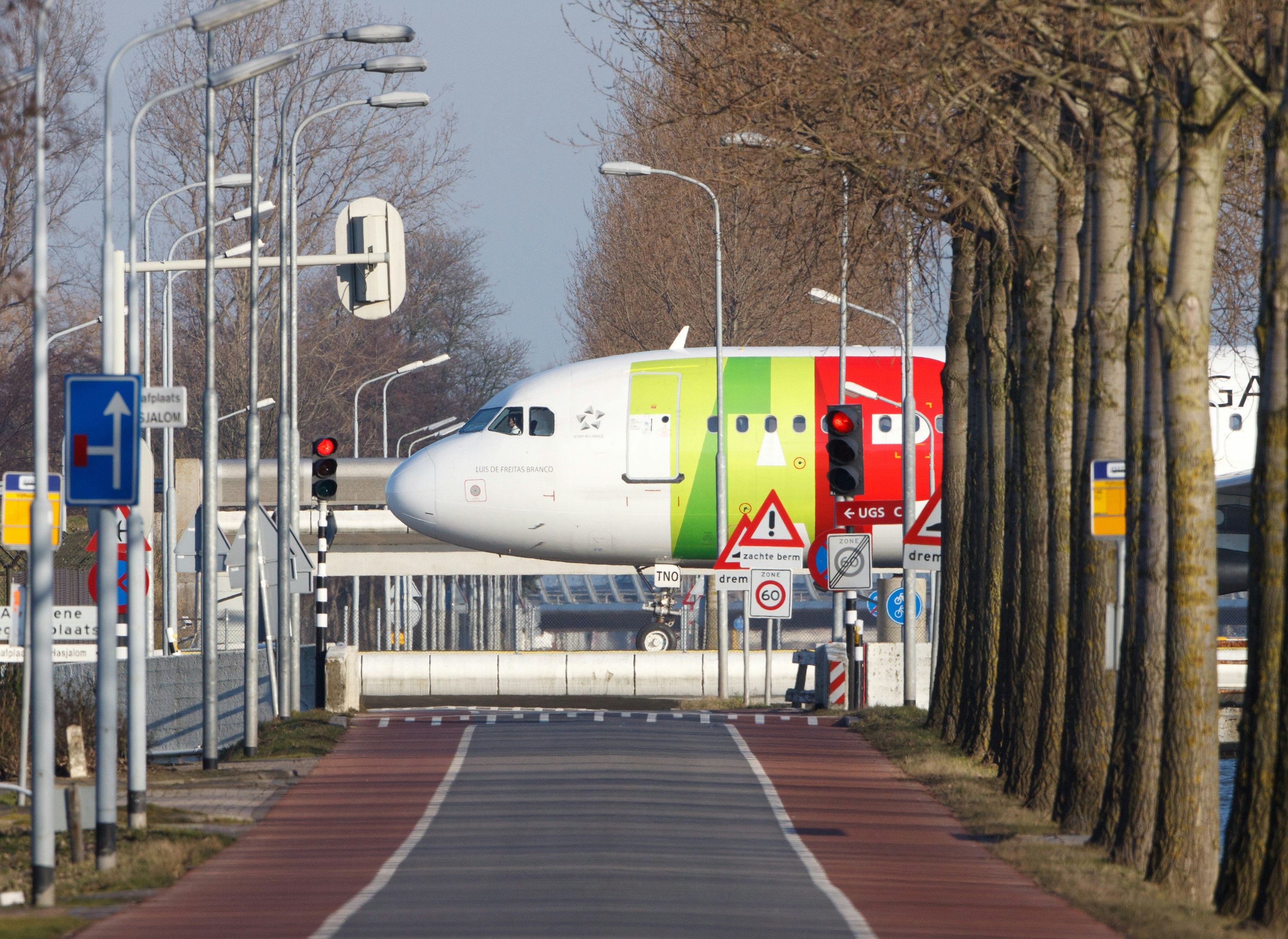 a large jetliner sitting on top of an airport runway, Airbus A320 TAP Portugal taxiing for take off to the Polderbaan runway 36L Schiphol Amsterdam Holland the Netherlands second. Canon 500mm
