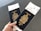 A hand holding two Canadian passports, each containing a boarding pass. The passports are navy blue with gold text and the Canadian coat of arms embossed on the cover. The background is neutral and out of focus.