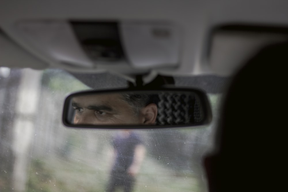 a man is seen in the rear view mirror of a vehicle