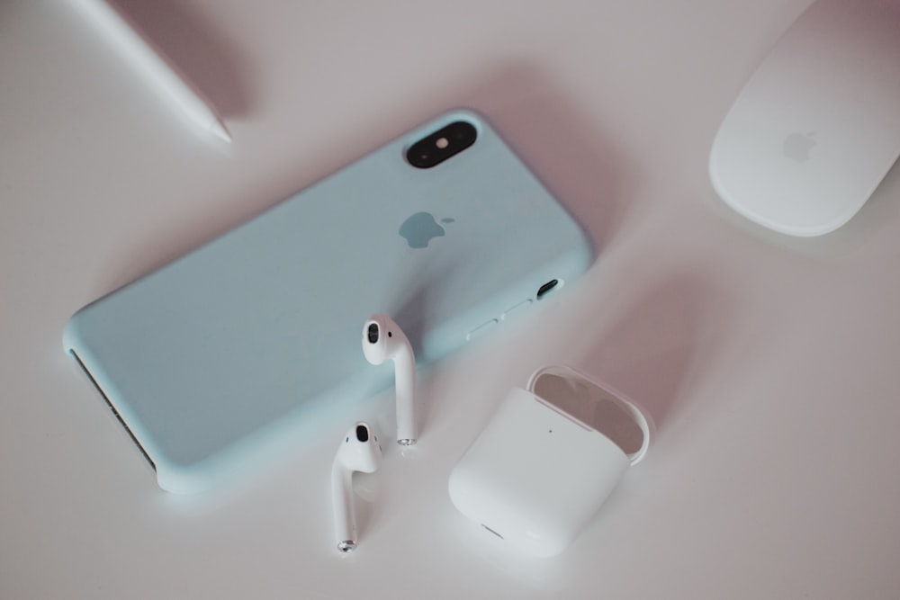 Un iPhone, auricolari e cuffie su un tavolo
