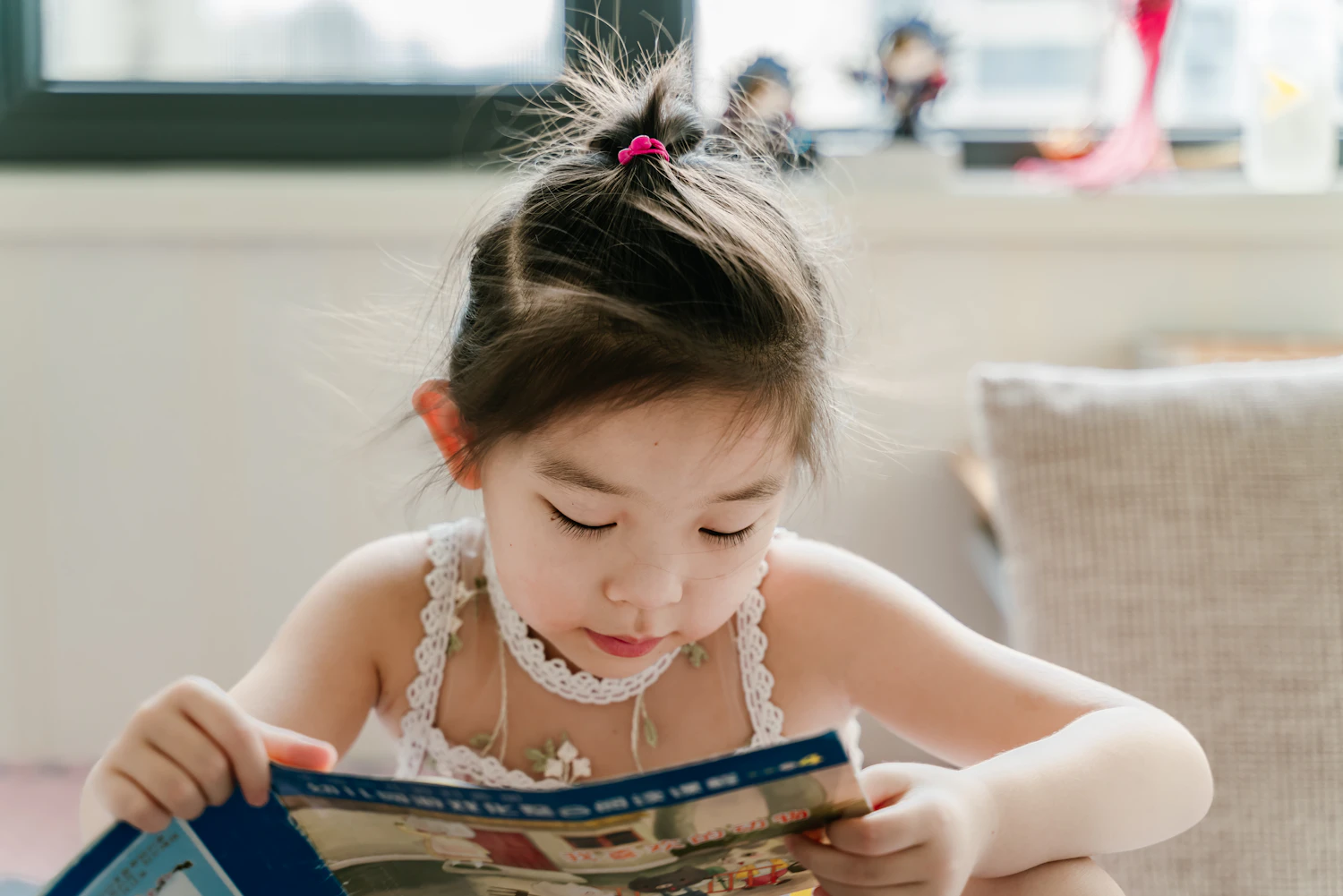 A young child curled up calmly with a book at home