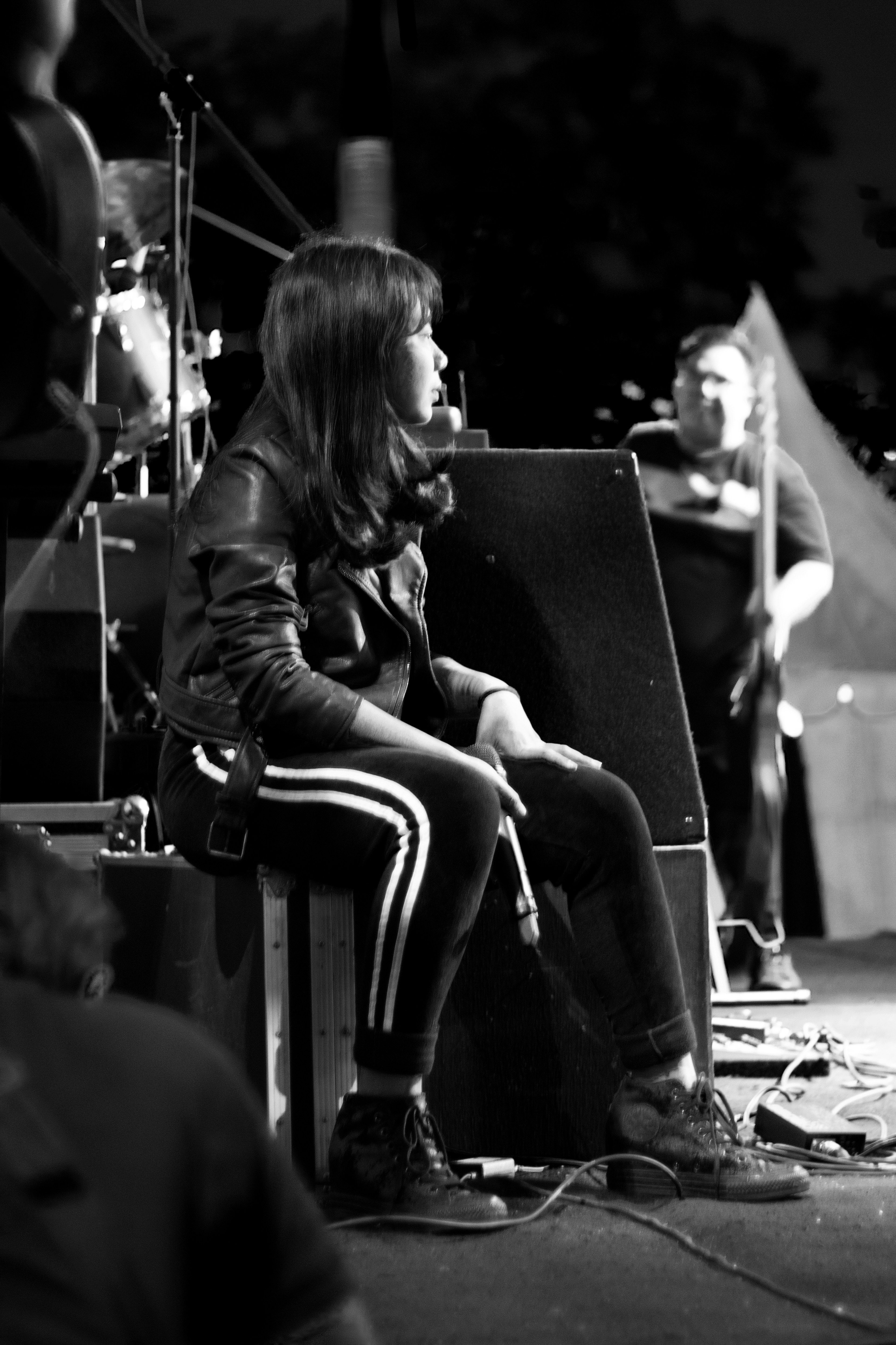 Girl band singer is sitting on the stage holding mic and waiting to show