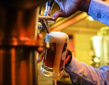 A bartender expertly pouring a craft beer into a glass framed by warm pub lighting