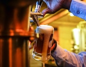 Bartender pouring a cold beer in a lively, welcoming bar setting.