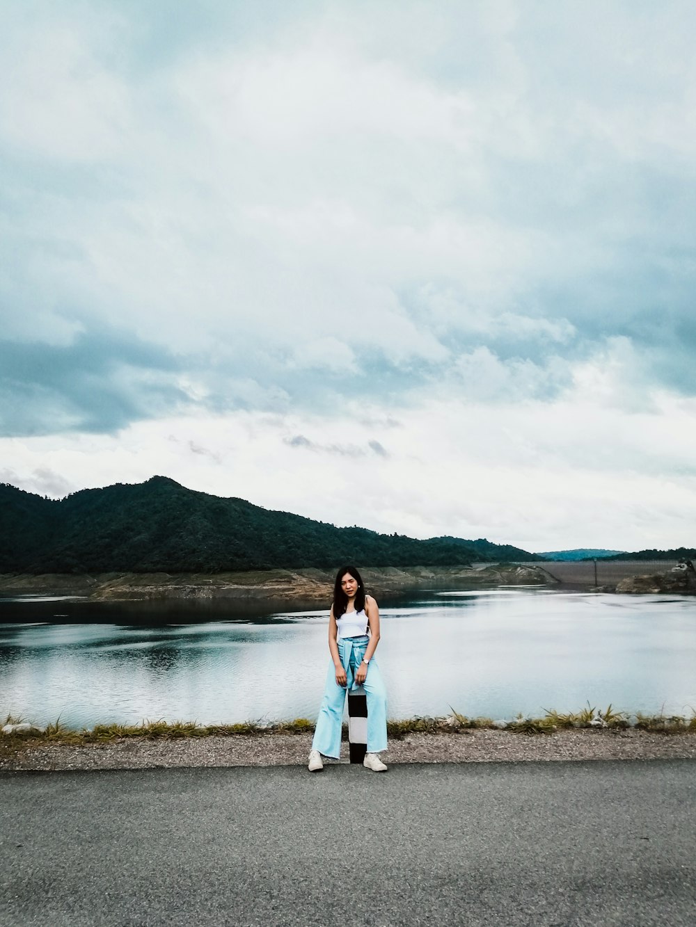 woman in white sleeveless shirt sitting near body of water during daytime