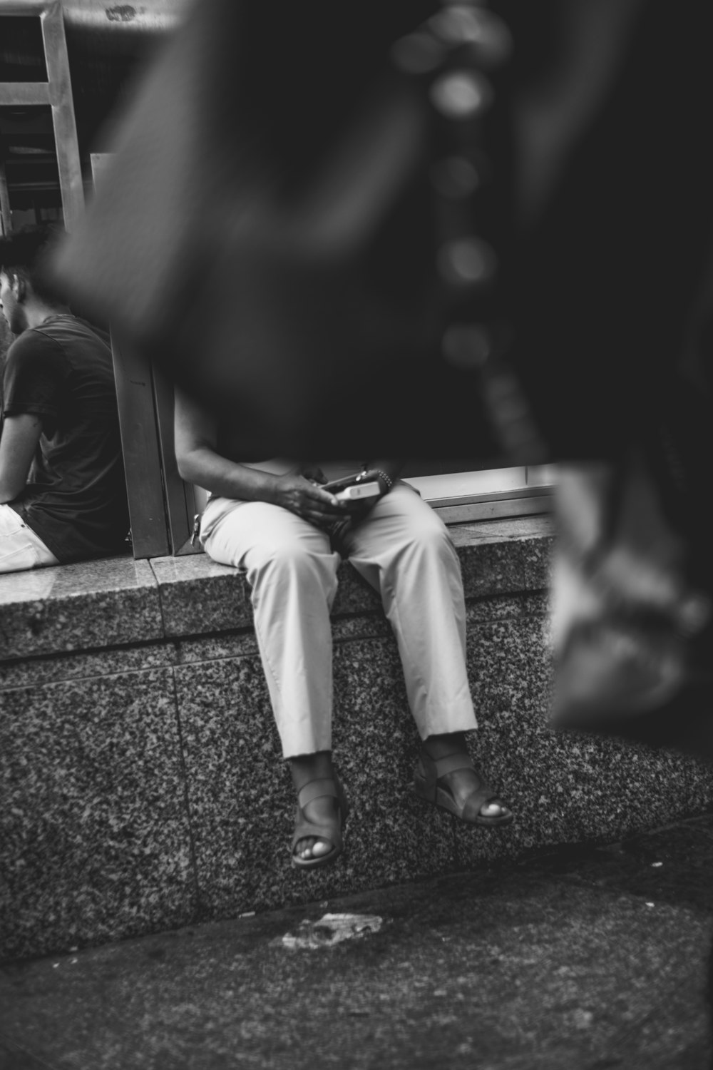 a man sitting on a ledge next to a building