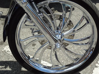 Close-up photo of a sleek motorcycle wheel with a shiny CNC racing rim under dramatic lighting.