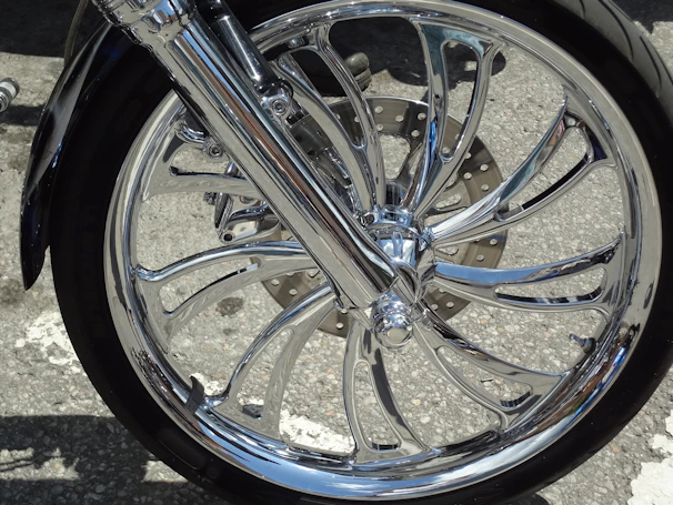 Close-up photo of a sleek motorcycle wheel with a shiny CNC racing rim under dramatic lighting.
