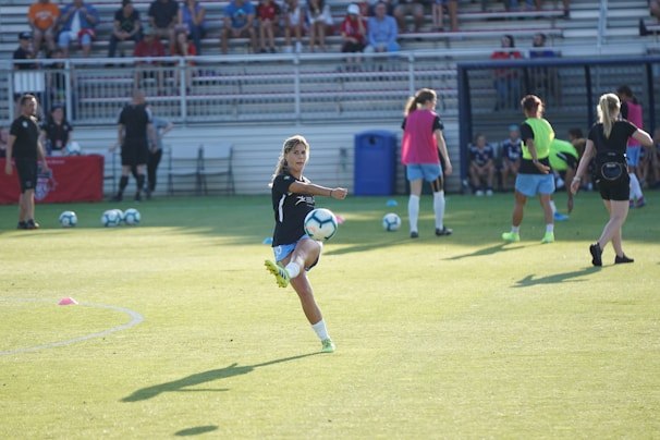 A dynamic shot of a female soccer player mid-kick, showcasing strength and focus on the field.