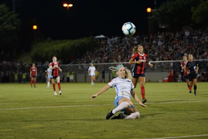 Action shot of a soccer match with players diving for the ball under stadium lights