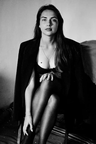 Portrait of a woman dressed in a monochrome tailored jacket against a plain backdrop reflecting understated sophistication.