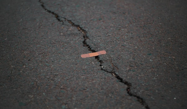 a small band-aid, put on top of a large crack in the asphalt sidewalk
