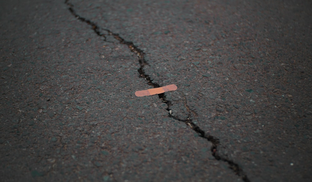orange band aid on concrete surface crack
