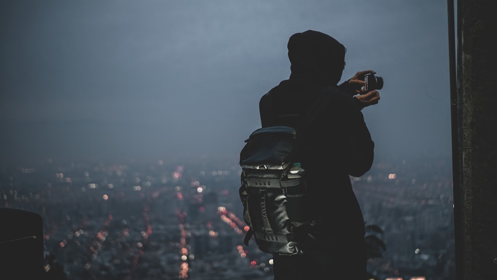 person carrying backpack holding black camera