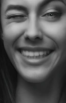 A close-up of a smiling woman with a playful, inviting gaze.