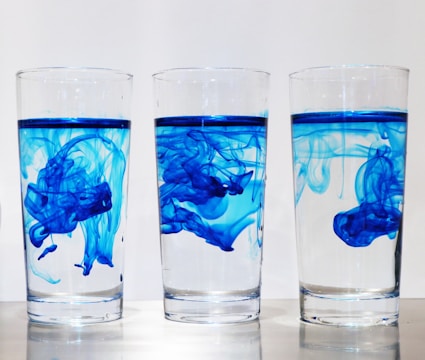 Close-up of hands moving colored water layers between glasses in the game.