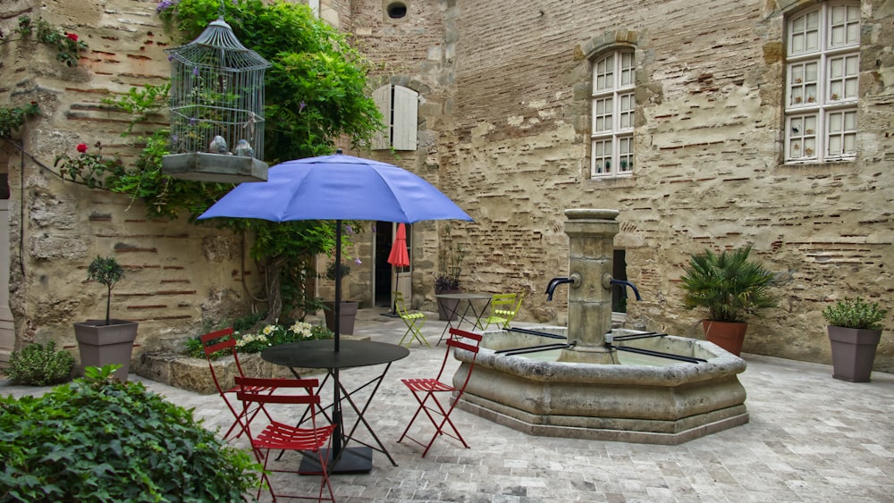 blue patio umbrella beside fountain