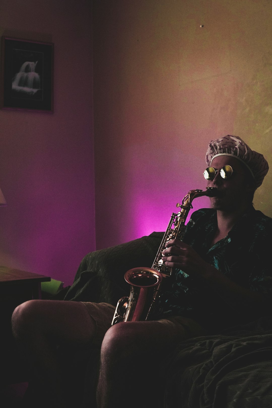 man sitting while playing brass saxophone
