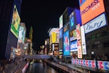 Nighttime scene of a shopping district illuminated by vibrant digital outdoor displays.