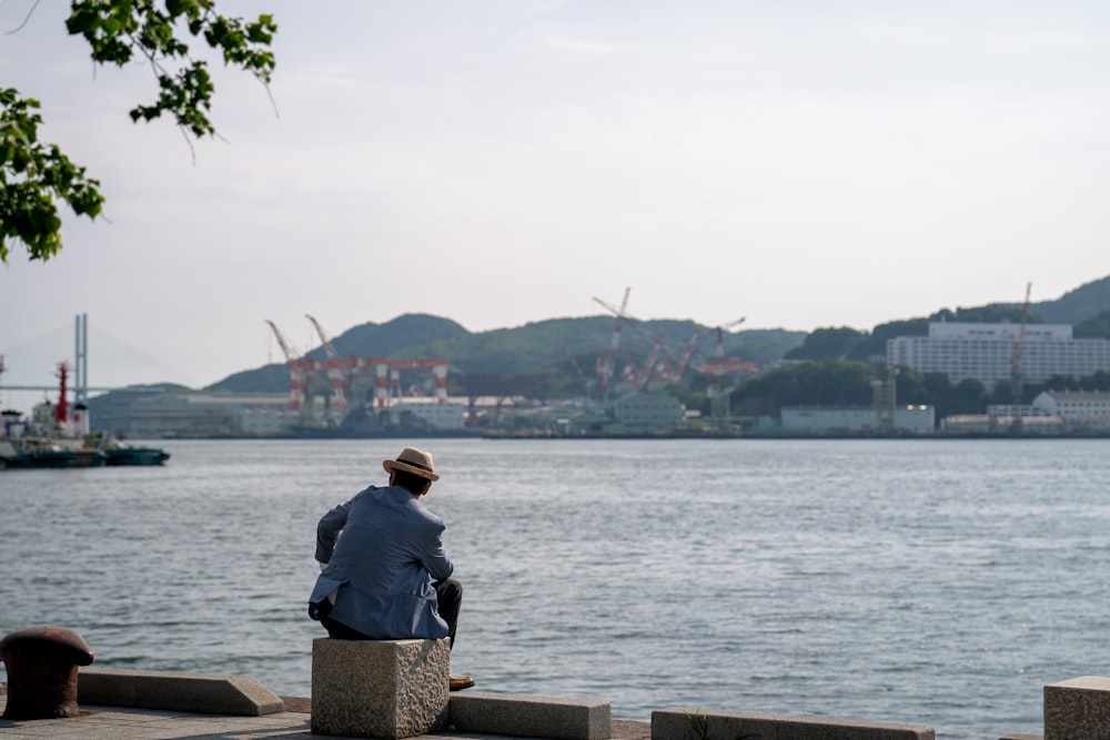 man sitting on rock looking on water