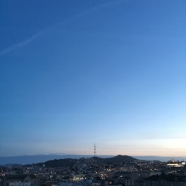 A panoramic view of a luxury high-rise building illuminated at dusk against a dark gray sky.