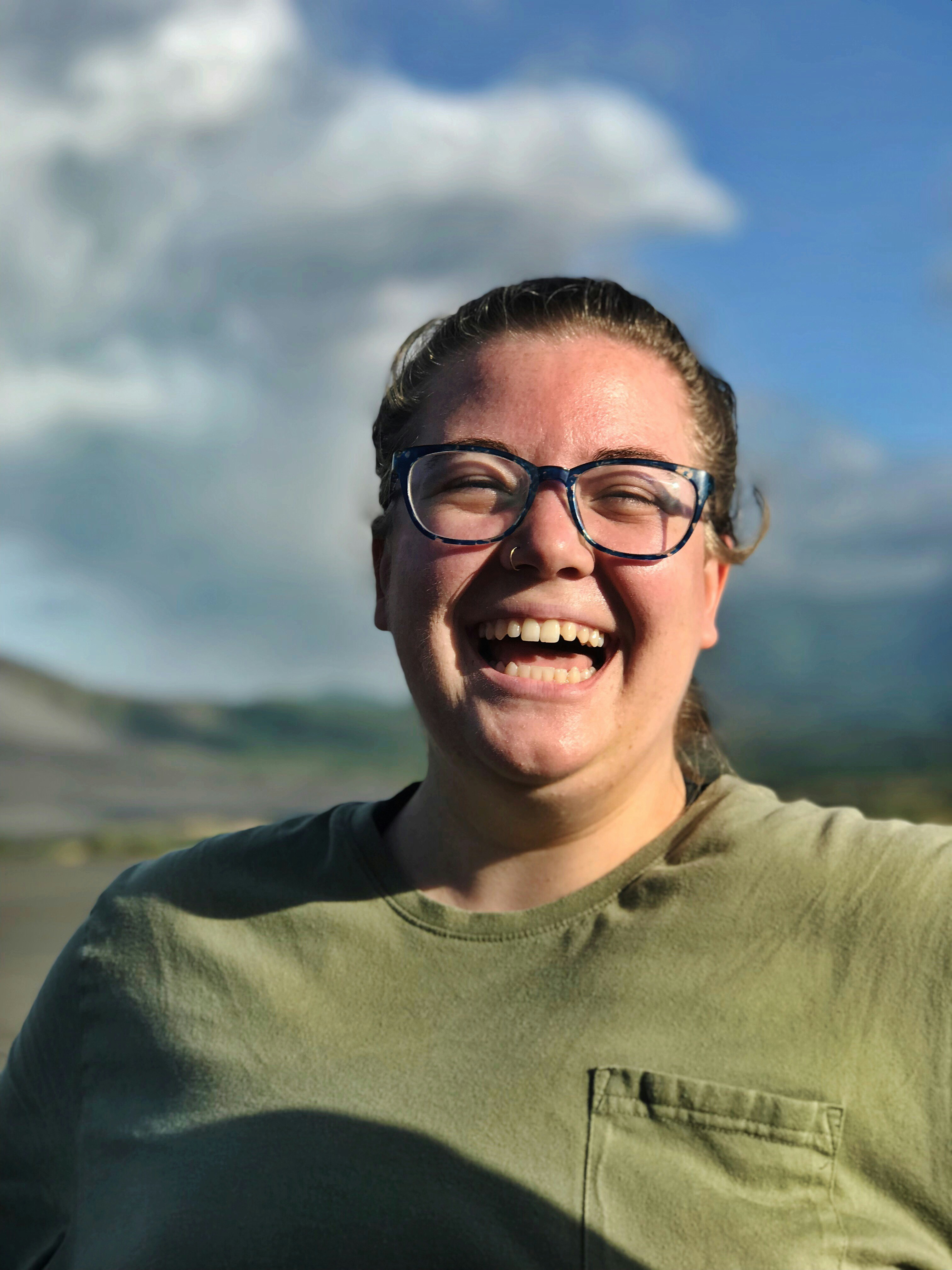 Mujer con gafas y camisa verde con bolsillo de cuello redondo