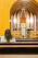 A warm photo of a smiling woman sitting peacefully inside a sunlit church pew.